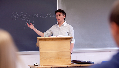 Lecturer standing in front of a podium, lecturing a class.