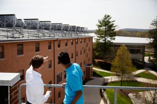 Two students looking across campus from the top of a building.