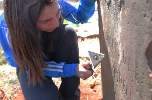 Student cleaning a gravestone at Asper Burial Ground