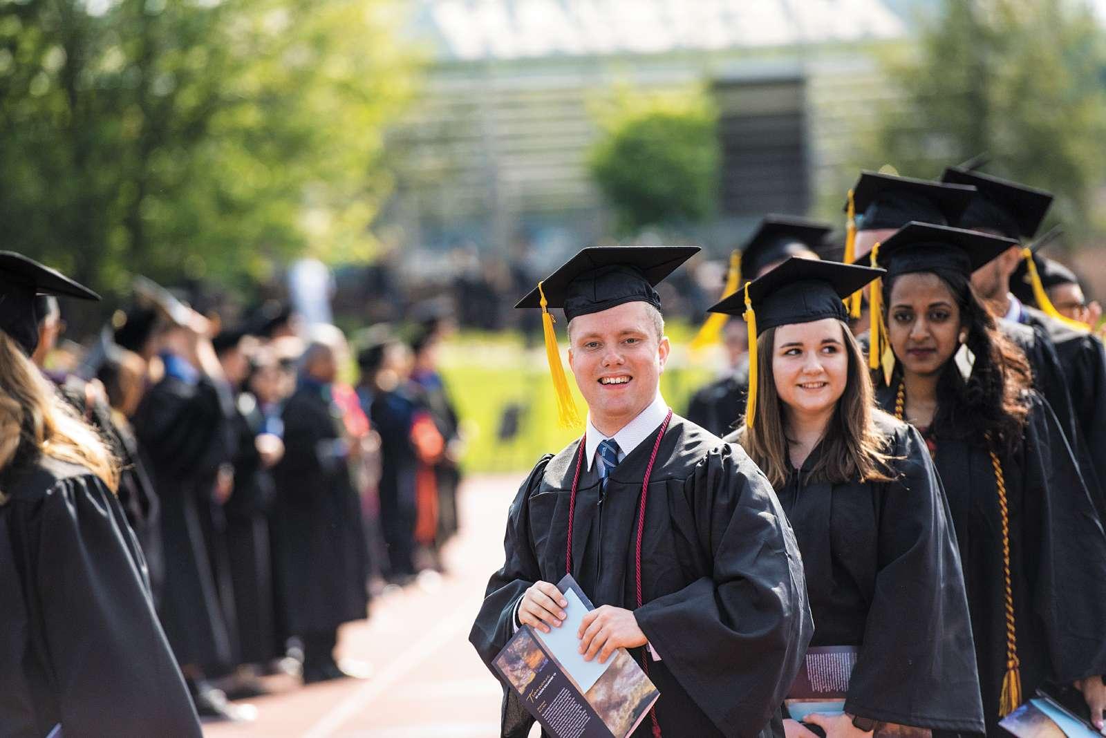 students walking in caps and gowns at commencement