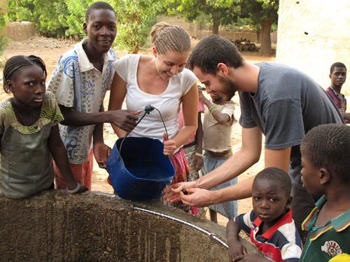 A group of African children surrounding a well.