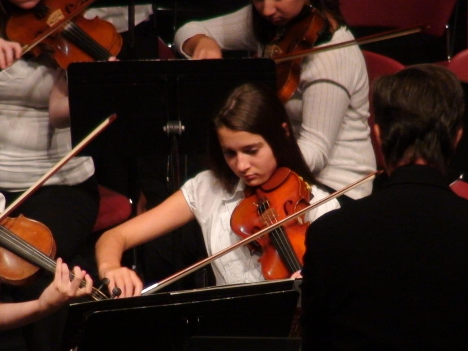A female violinist in an orchestra.