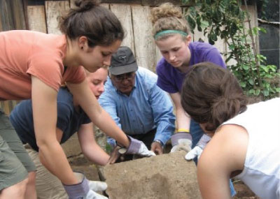 Students from Agapé center working together to move dirt from a field.
