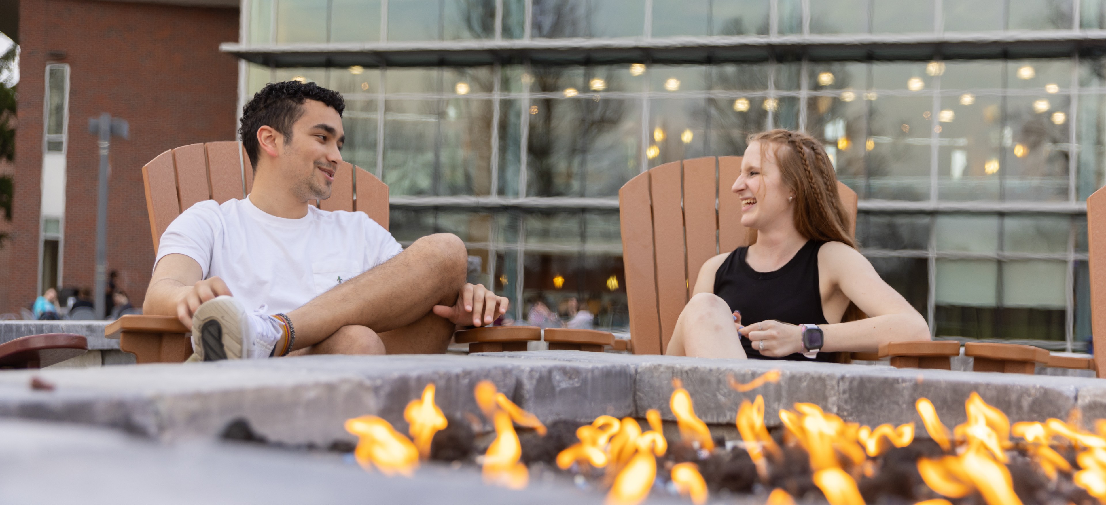 Two students talk in front of firepit