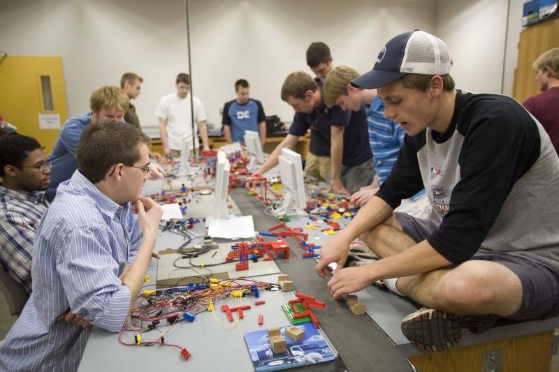 Engineering students putting together a large Lego project around a table