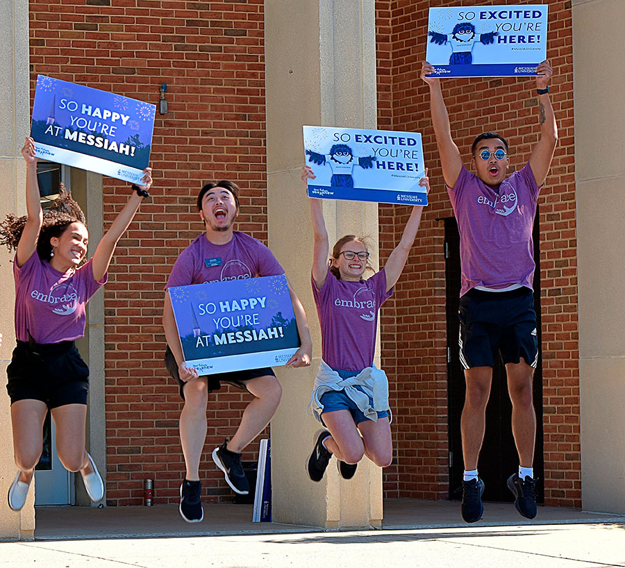 Four Messiah students jumping for joy at welcoming new students!