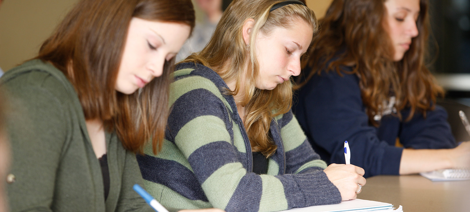Creative Writing Minor or Concentration Three female creative writing students writing something in their notebooks.jpg