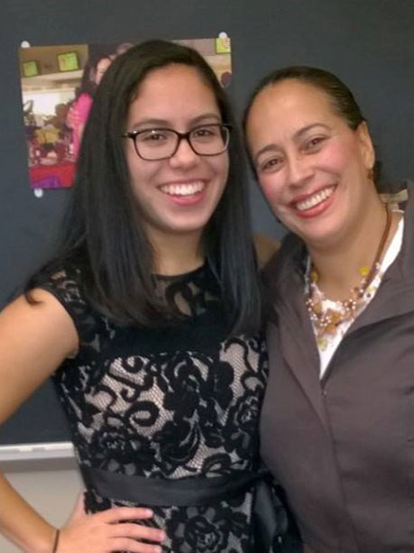 two women with dark hair pose side by side.