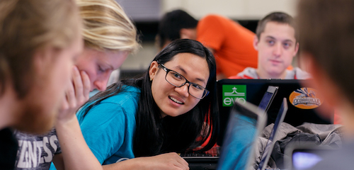 Student in classroom talking to other students at a table