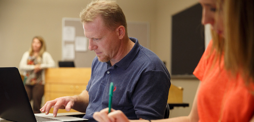 Student in classroom talking to other students at a table
