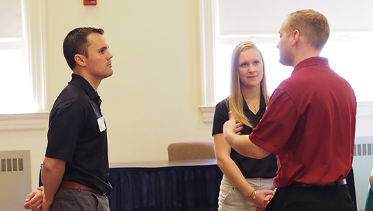 Three professionals engaged in a discussion during a networking event.