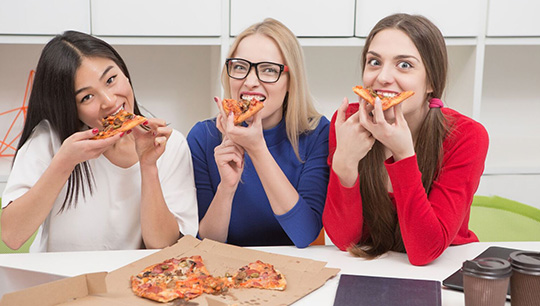 Three female students enjoying pizza