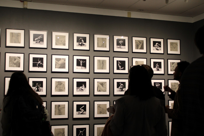 People standing in front of a wall of figurative photographs and drawings
