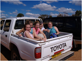 Students riding in the back of a pickup truck in the African bush