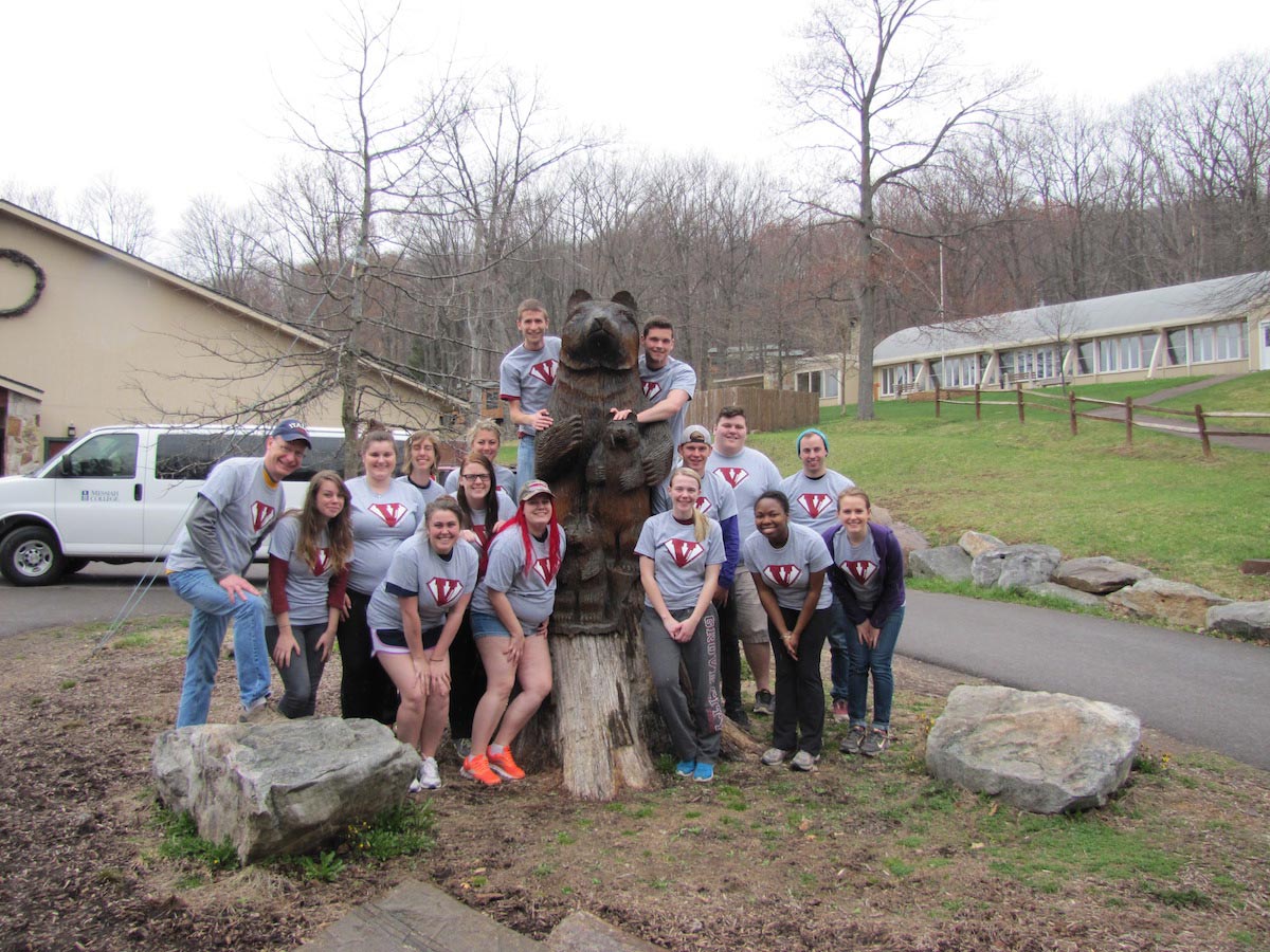 Groups of students pose with bear sculpture.