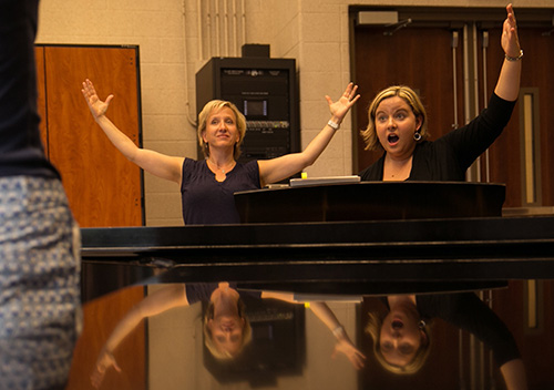 Pianist and music professor giving singing instructions.