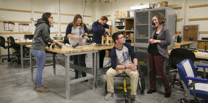 Students and a professor stand in the engineering workshop