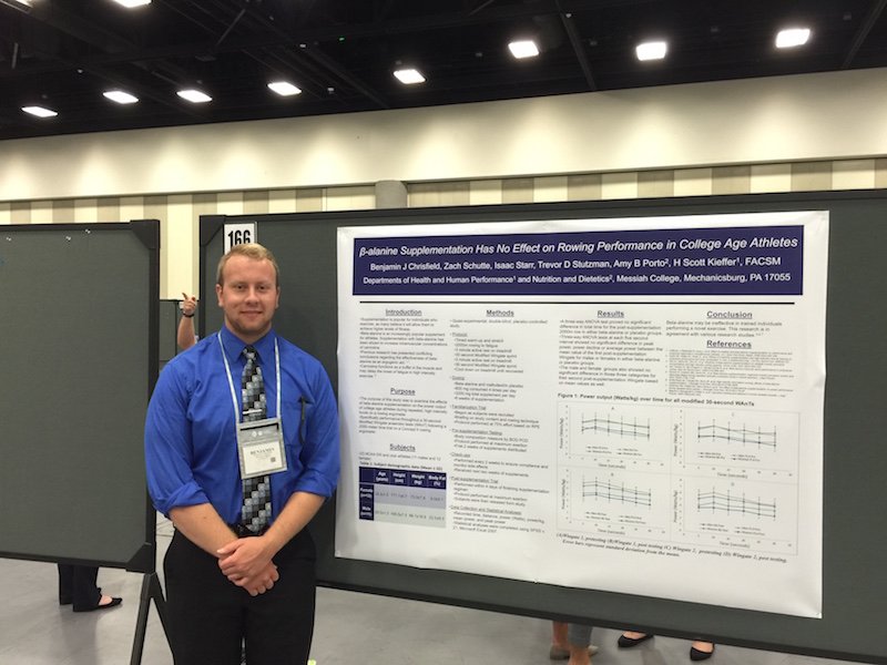 Benjamin Chrisfield standing next to his presentation poster.