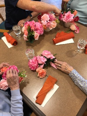 The hands of older people putting flower bouquets together.
