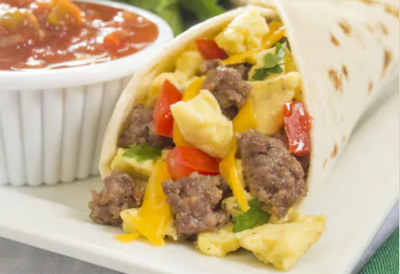 A breakfast tortilla filled with sausage, eggs and peppers next to salsa.