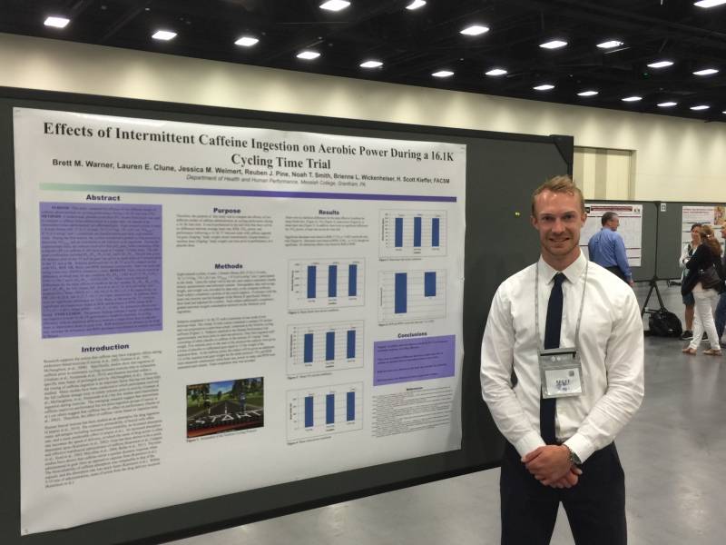 Brett Warner standing next to his presentation poster.