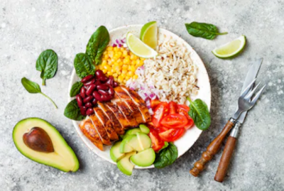 A burrito bowl on a plate shows an avocado, meat, rice, beans and veggies.