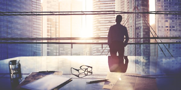 A man stands in a large window in a corporate office.