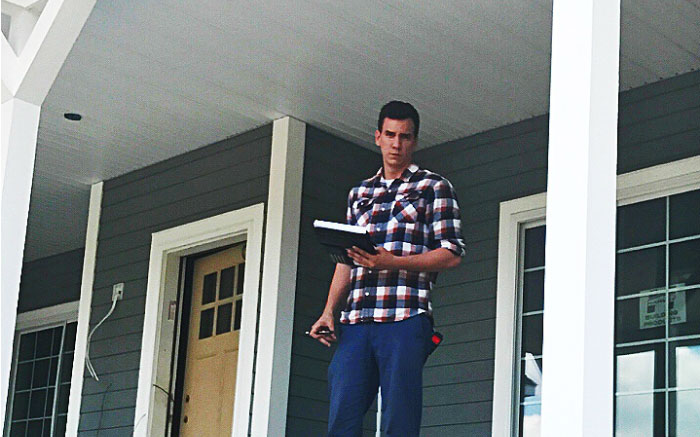Chad Gibson, 2015 alumnus, working on a house, standing next to a pole.