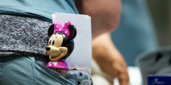 A Mini Mouse toy sticks out of the pocket of a hospital worker.