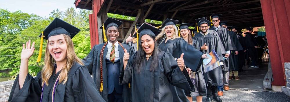 Graduating seniors walk across the covered bridge on Commencement morning