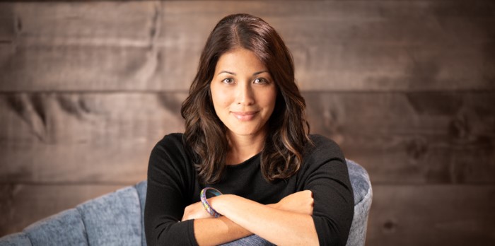 A headshot of a female author sitting in a chair.