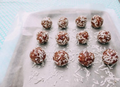 Date balls covered in coconut flakes on a baking sheet.