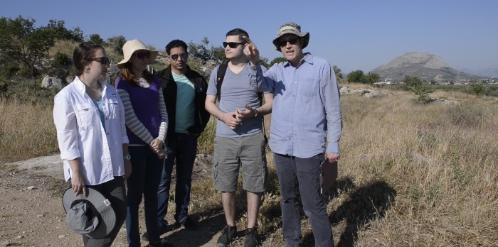 A man stands with a group of students in a desert