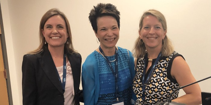 Three women stand together for a photo.