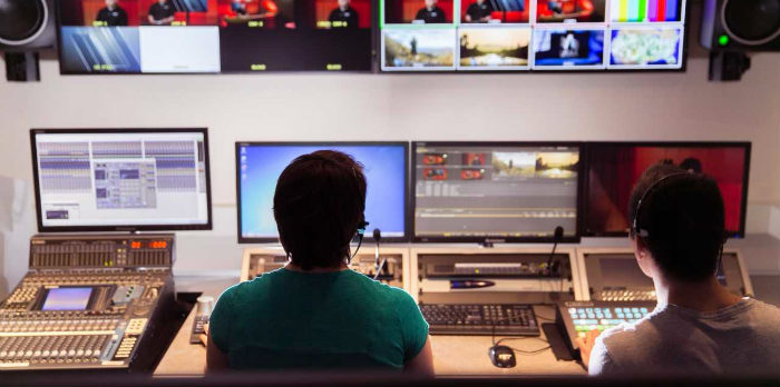 Students in front of television screens and a control panel in the studio.