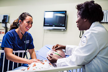 Nursing student and instructor in sim lab.