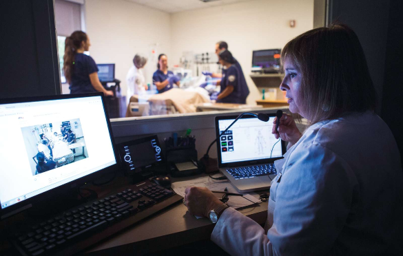 Photo of faculty monitoring nursing student simulation