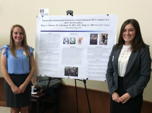 Two female students standing next to a poster of their research project.
