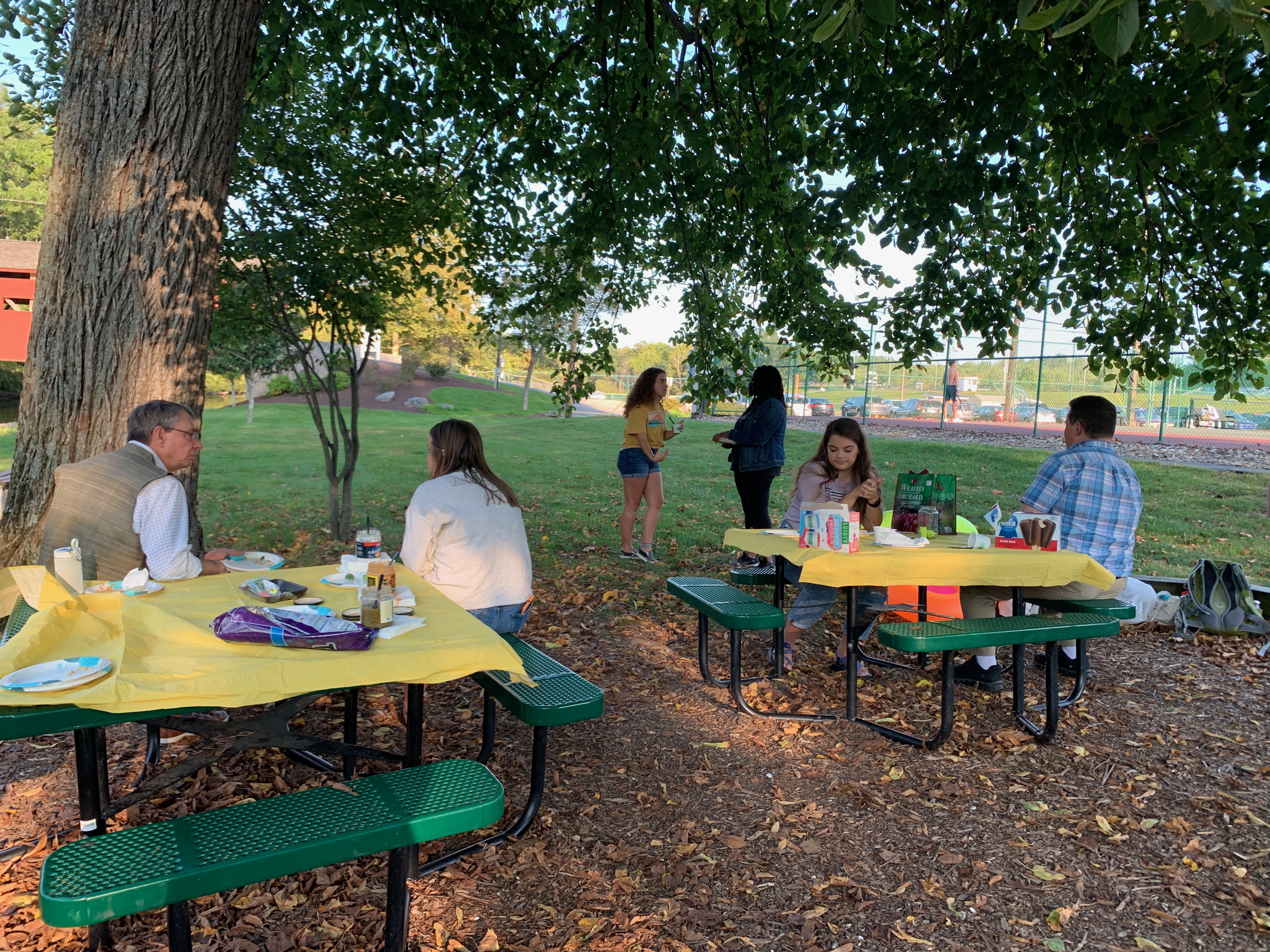 female and male students talking around picnic tables near the yellow breeches park