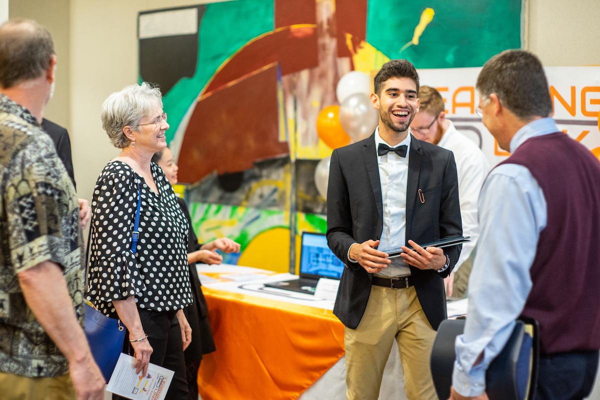 student talking with professors at reception