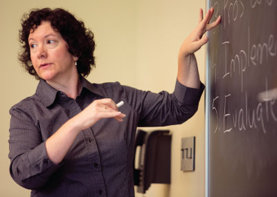 A teacher teaching in class, writing on the black board.
