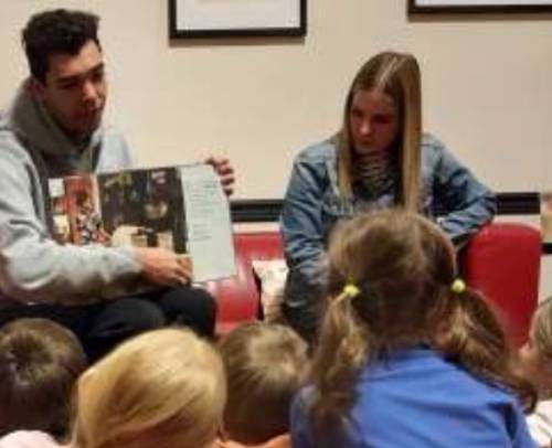 Messiah students reading a book about Martin Luther King Jr. to children from JOY Center.