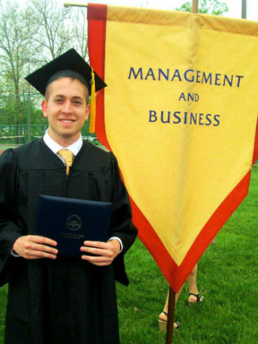 Jordan in front of the business banner at graduation