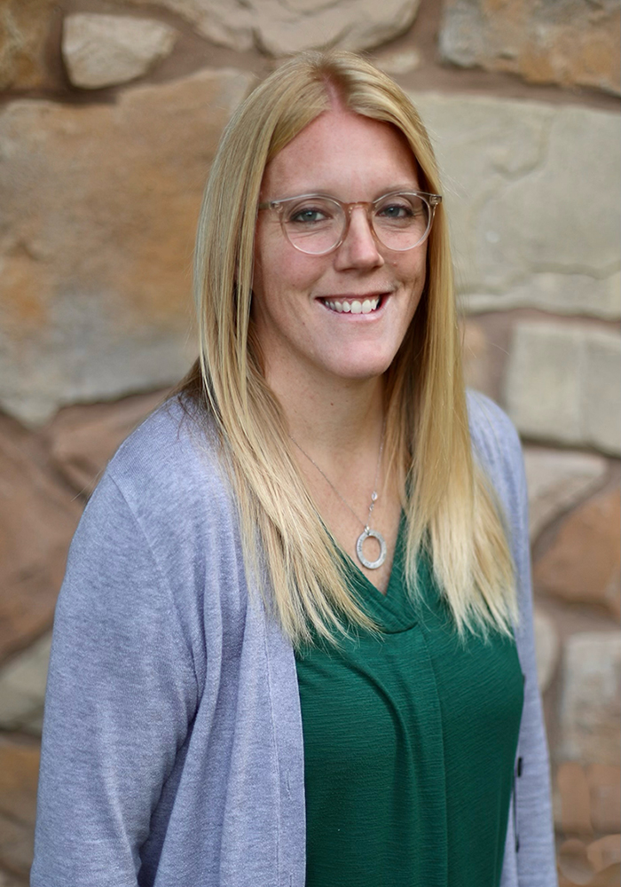 A headshot of Kelly Clancy. She is wearing a green shirt with a light gray cardigan over the top.