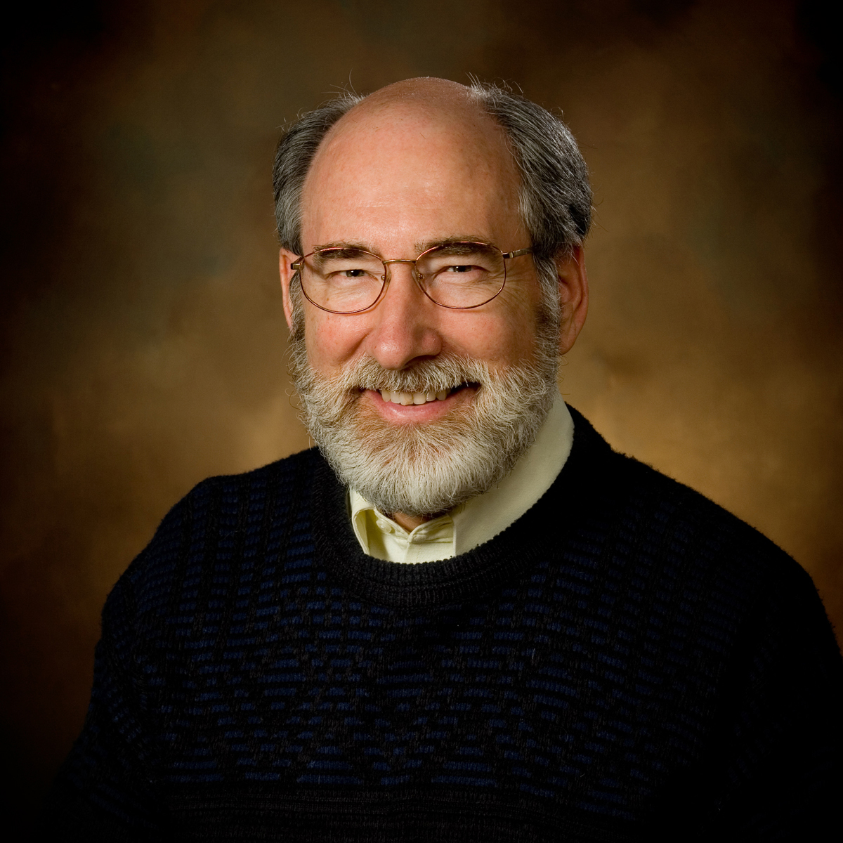 Profile headshot of a male professor wearing a white collared shirt under a black sweater