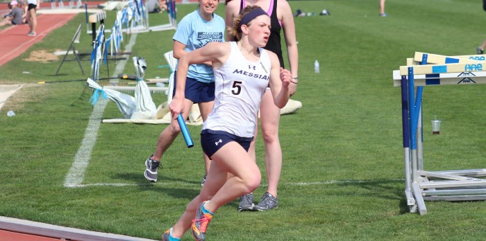 A female track runner runs with a baton in hand.