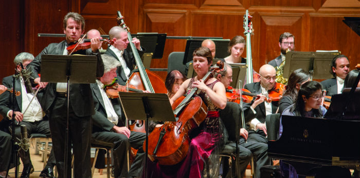 An orchestra sits on a stage playing various instruments.