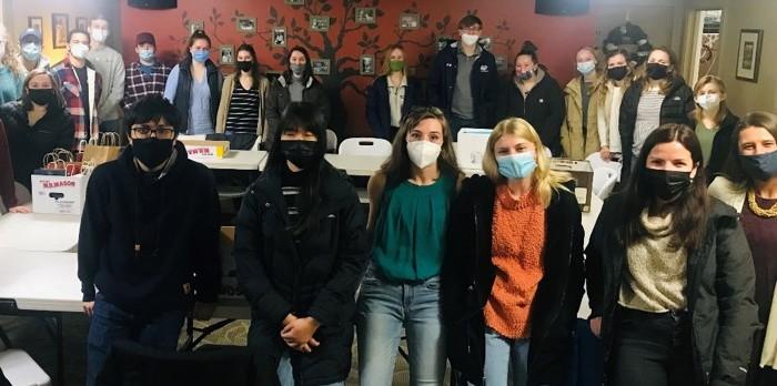 A group of students standing around a table with masks on.