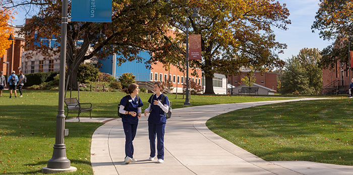 Two nursing students walk on a brick path