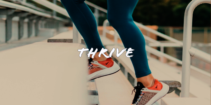 Only the feet of a person walking up stairs with sneakers on and the words "thrive" written over the photo.